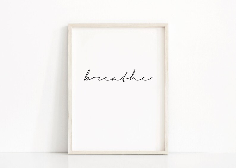 K&ouml;nnte beinhalten: Ein wei&szlig;er gerahmter Druck mit dem Wort "breathe" in schwarzer Kursivschrift.