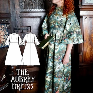 May include: A long dress with a high collar and wide sleeves, patterned with a detailed, fantastical print in green, blue, and cream. A person is holding a book. The text "THE AUBREY DRESS" is displayed at the bottom of the image.