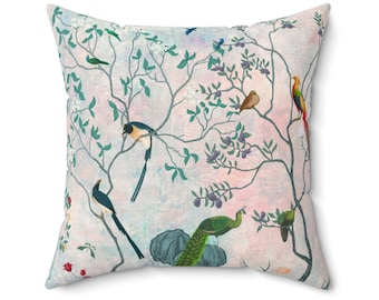 May include: A square throw pillow with a pink and blue watercolor background featuring a stylized tree with green leaves and branches.  The tree is decorated with colorful birds, including a peacock, a pheasant, and several smaller birds.