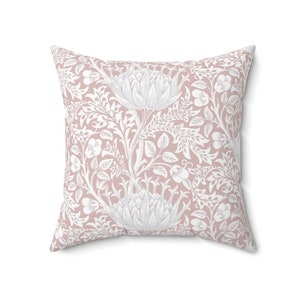 May include: A pink throw pillow with a white floral pattern. The pattern features stylized flowers and leaves.