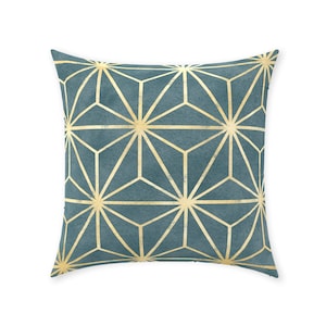 Puede incluir: Una almohada azul turquesa con un patrón geométrico dorado. El patrón está formado por triángulos y estrellas superpuestos.