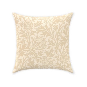 May include: A beige throw pillow with a floral pattern. The pattern is a repeating design of stylized leaves and flowers.