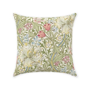 May include: Square throw pillow with a floral pattern. The design features large, stylized flowers in shades of yellow, pink, and blue, set against a cream-colored background. Green leaves and stems intertwine throughout the pattern.