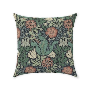 May include: A square throw pillow with a floral pattern. The pillow features a dark blue background with a repeating pattern of red, white, and green flowers.