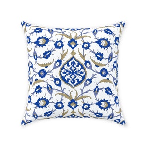 May include: A white cushion with a blue and gold floral pattern. The pattern is reminiscent of traditional Turkish or Middle Eastern designs.