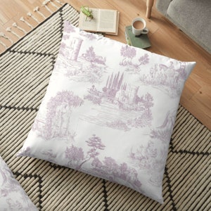 May include: A square floor pillow with a white background and a lavender toile pattern. The pattern depicts scenes of buildings, trees, and figures. The pillow is placed on a black and white patterned rug.
