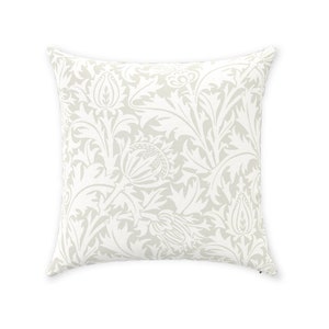 May include: A white throw pillow with a beige floral pattern. The pattern features stylized leaves and flowers.