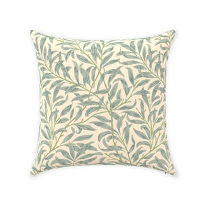 May include: A square throw pillow with a cream background and a repeating pattern of green willow branches.
