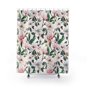 May include: White shower curtain with a floral pattern of pink and white magnolia flowers and green leaves.