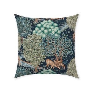 May include: A square throw pillow with a dark blue background featuring a repeating pattern of stylized trees, a stream, and deer. The trees are green and brown with intricate details. The deer are brown with antlers.