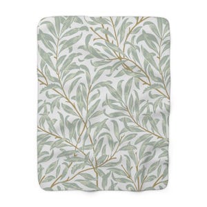 May include: A soft, white blanket with a repeating pattern of green leaves and branches. The leaves are stylized and have a vintage look.