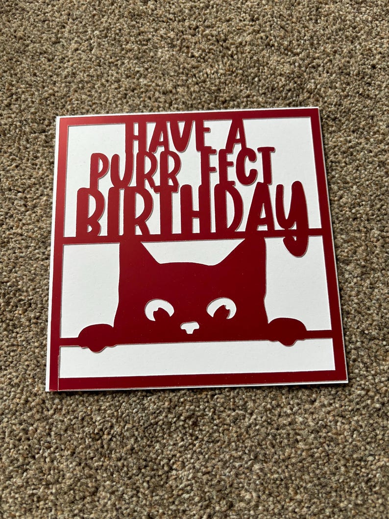 K&ouml;nnte beinhalten: Rote Karte mit wei&szlig;em Hintergrund und einer roten Katze, die &uuml;ber den Rand schaut. Die Karte sagt "Have a purrfect birthday".