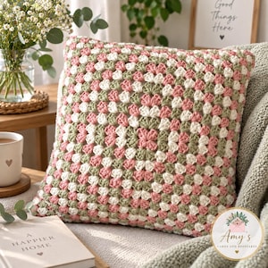 May include: A square crochet pillow cover featuring a classic granny square pattern in alternating shades of sage green, dusty rose pink, and cream white. The textured yarn design creates a repeating geometric motif across the entire surface.
