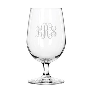 May include: A clear glass wine goblet with a stem and a wide bowl. The glass is etched with the monogram "LKS" in a decorative script. The goblet is designed for wine.