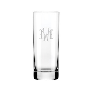 Puede incluir: Un vaso alto de vidrio transparente con un monograma "MW" grabado en la parte delantera.
