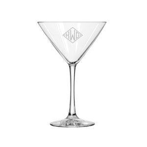 May include: A clear glass martini glass with a diamond-shaped monogram etched on the front. The monogram reads "KWG".