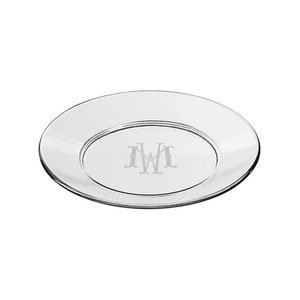 May include: A clear glass charger plate with a monogrammed initial "M" etched in the center.
