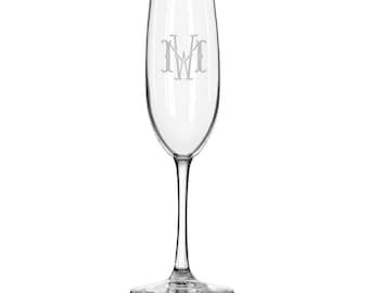 May include: A clear glass champagne flute with a monogrammed "NW" etched on the front.