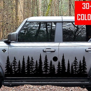May include: A gray SUV with a black silhouette of a forest scene on the side door. The scene includes trees and a small circle. The text "30+ COLORS" is in a red box on the upper right corner of the image.