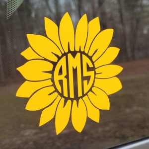 May include: A yellow sunflower decal with a black circle in the center. The circle contains the letters "RMS" in a black, stylized font.