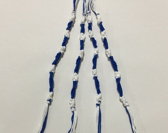 May include: A blue and white friendship bracelet with a knotted design. The bracelet is made of string and has a black elastic band at the top.