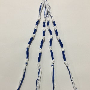 Peut inclure: Un bracelet d'amitié bleu et blanc avec un motif noué. Le bracelet est fait de ficelle et a un élastique noir en haut.