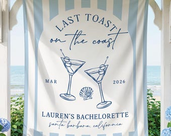 May include: A rectangular fabric banner featuring vertical light blue and white stripes. The centre displays the text "LAST TOAST on the coast", two martini glasses with olives, a seashell, "MAR 2026", and "LAUREN'S BACHELORETTE santa barbara, california".