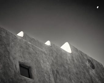 May include: A black and white photograph of a building with a textured exterior. The building has a series of triangular shaped windows.