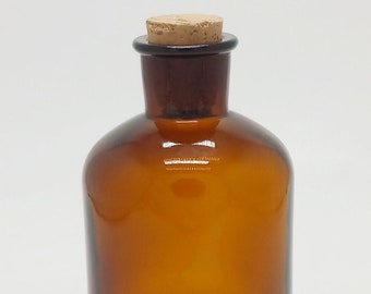 May include: A brown glass bottle with a cork stopper. The bottle is empty and has a rounded shape.