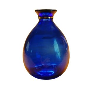 May include: A cobalt blue glass vase with a rounded body and a wide mouth. The vase has a gold rim around the top.