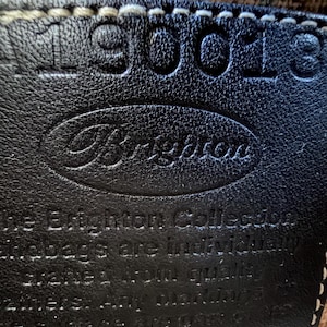 Op de afbeelding: Een zwarte leren patch met witte stiksels voorzien van de in reli&euml;f aangebrachte tekst Brighton en het nummer 190018. De tekst luidt: The Brighton Collection handbags are individually crafted from quality leathers. Any markings on the surface are part of its natural beauty, texture, and character of the leather.