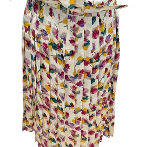 May include: A white pleated skirt with a floral print in shades of pink, purple, yellow, and green.