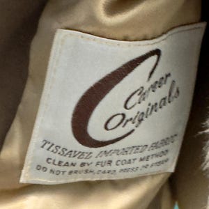 May include: A white label with brown text that reads "Career Originals" and "Tissavel Imported Fabric". The label also includes instructions for cleaning the fabric: "Clean by fur coat method. Do not brush, card, press or steam."