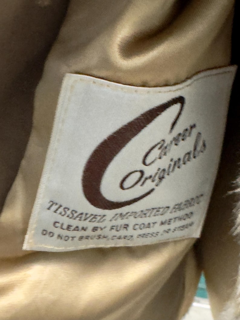 May include: A white label with brown text that reads "Career Originals" and "Tissavel Imported Fabric". The label also includes instructions for cleaning the fabric: "Clean by fur coat method. Do not brush, card, press or steam."