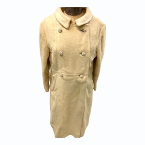 May include: A cream-colored double-breasted coat with large pearl-like buttons.