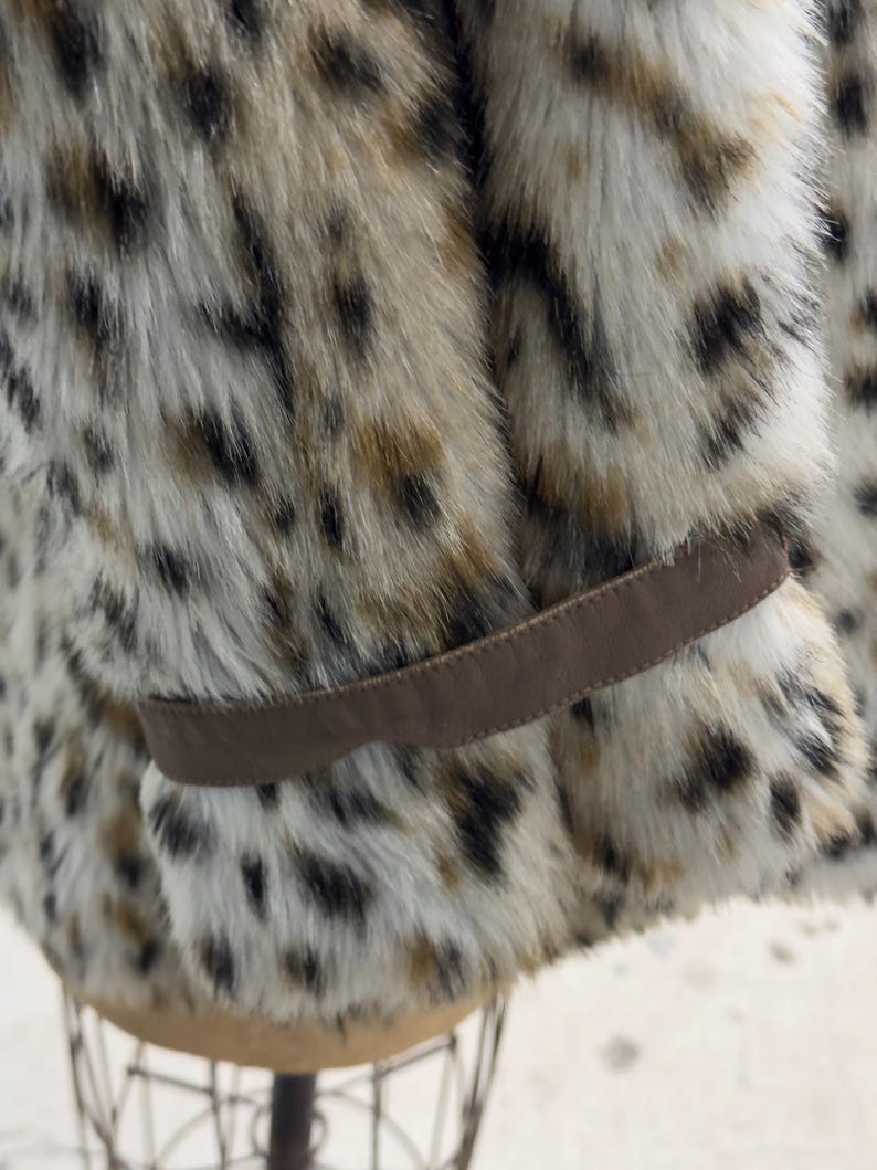 May include: A brown faux fur jacket with a leopard print pattern. The jacket has a brown leather belt.