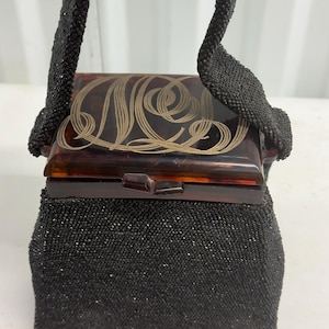 Bolso tipo caja con cuentas negras de los años 40 y monograma en lucita color ámbar