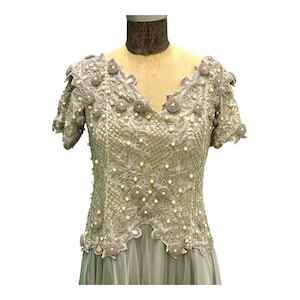 Pode incluir: Um vestido formal cinza claro com um corpete de renda com contas e uma saia fluida.