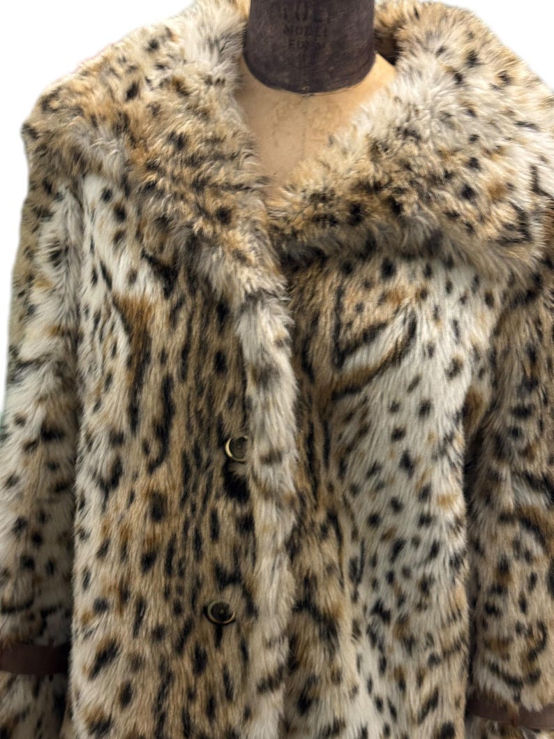 May include: A brown and white leopard print faux fur coat with a large collar and button closure.