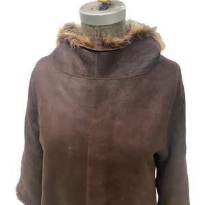 May include: A brown leather jacket with a fur collar. The jacket has a long sleeve and a zipper closure.