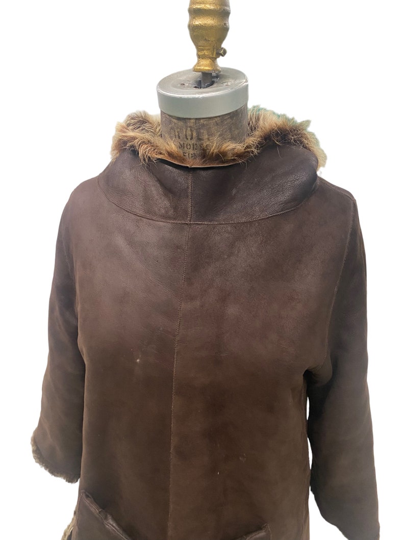 May include: A brown leather jacket with a fur collar. The jacket has a long sleeve and a zipper closure.