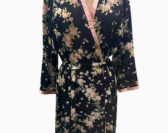 May include: Black floral print robe with pink trim and a matching belt. The robe features a delicate pattern of pink and yellow flowers on a black background. The robe is displayed on a mannequin.