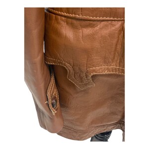 Peut inclure: Une veste en cuir marron avec un bouton sur la manche et un d&eacute;tail de couture d&eacute;coratif au dos.