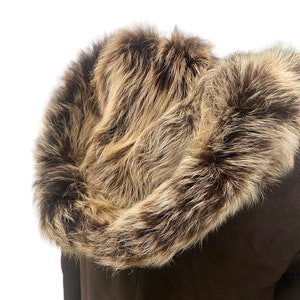 May include: A brown suede jacket with a large, fluffy fur hood. The fur is a mix of brown and beige.