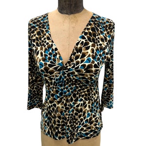 May include: A white, brown, and blue patterned long-sleeve top with a V-neckline.