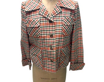 May include: A vintage, multi-colored plaid jacket with a button-up front, two chest pockets, and two lower pockets. The jacket is displayed on a mannequin. The plaid pattern includes red, green, orange, and white squares.