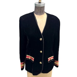 Può includere: Un blazer in velluto nero con bottoni dorati e bordi rossi e dorati sui polsini e sulle tasche.