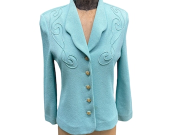 Pode incluir: Um blazer azul claro com botões dourados e um design bordado decorativo na gola. O blazer está em um manequim.