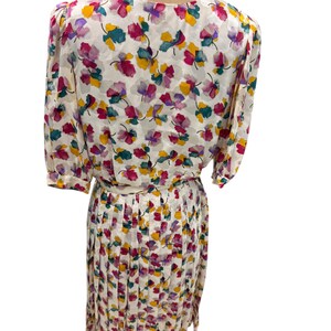 May include: A white dress with a floral print in shades of pink, yellow, green, and purple. The dress has a pleated skirt and a fitted bodice.