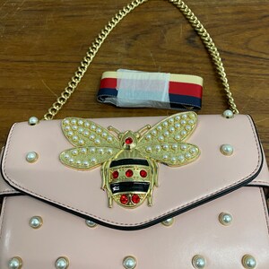 Bolso de mano con forma de mariquita de piel sintética color rosa y joyas doradas